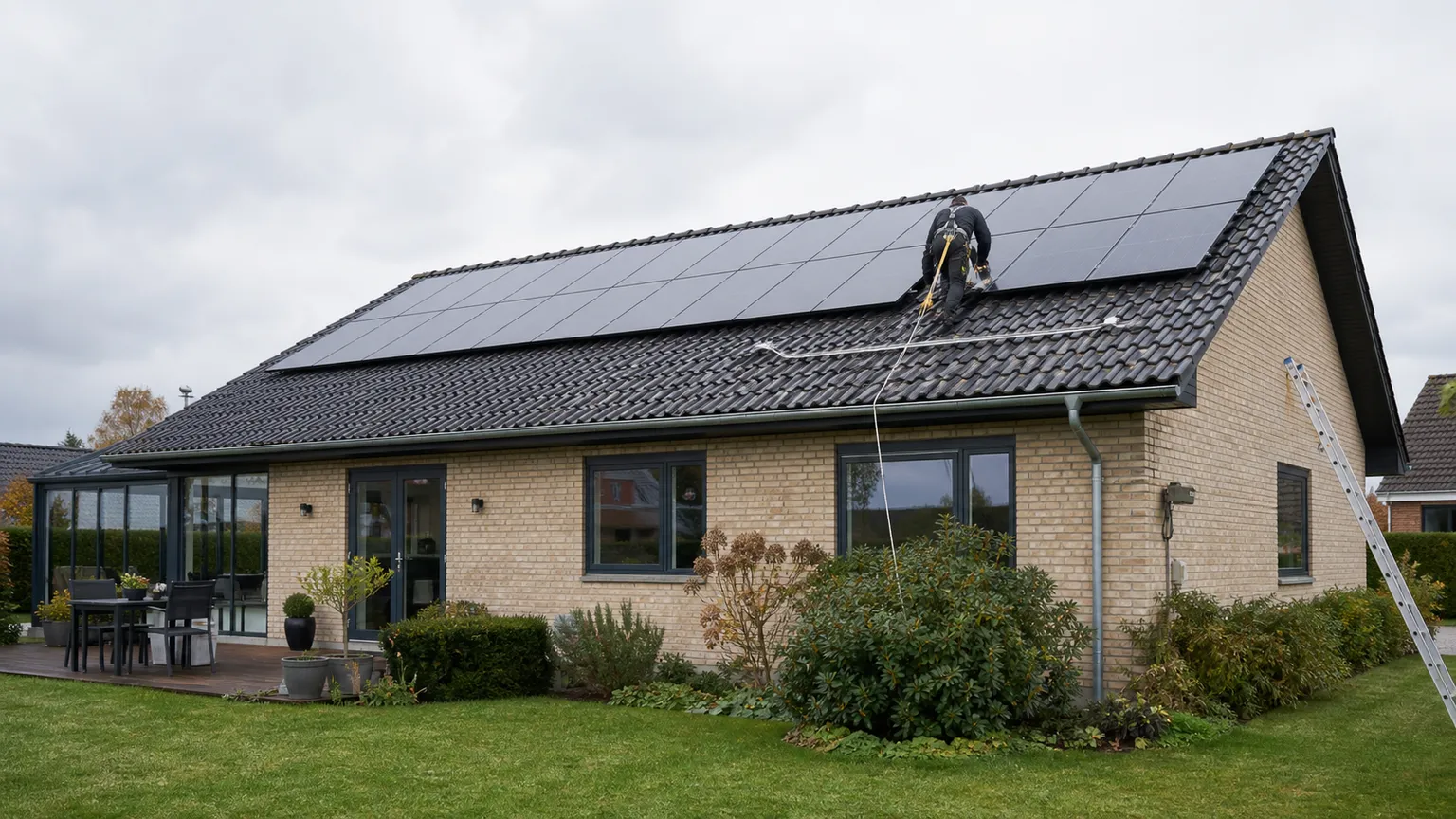 Montør med faldsikring arbejder på solceller på taget af et dansk parcelhus.